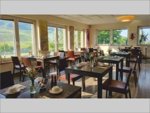 ein Esszimmer mit Tischen, Stühlen und Fenstern in der Unterkunft Christiana's Wein & Art Hotel in Bernkastel-Kues