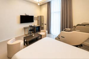 a hotel room with a bed and chairs and a tv at Brown Dot Hotel Ulsan Samsan in Ulsan