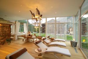 a living room with a chandelier and white chairs at Loftsuite Hotel Saas in Saas-Almagell