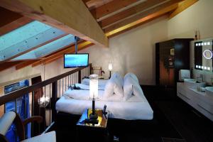 Schlafzimmer mit einem Bett mit weißen Kissen und einem TV in der Unterkunft Loftsuite Hotel Saas in Saas-Almagell