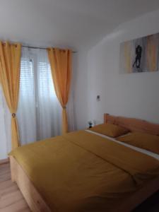 a bedroom with a bed with yellow sheets and curtains at Natalija apartmans in Sveti Juraj