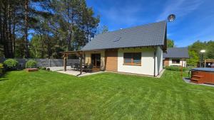 a small house in a yard with a grass yard at Domek Lipowy BALIA-jacuzzi in Sasino
