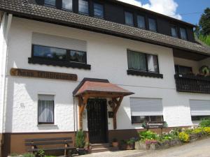 a white building with a wooden door and a bench at Haus Mühlgrund in Bad Wildbad