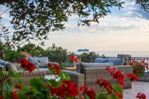 a patio with chairs and red flowers and the ocean at Vila Veslo in Begovići