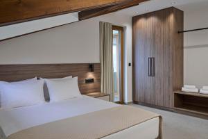 a bedroom with a white bed and a wooden wall at Villa Rock&SeaView in Livanates