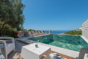 a swimming pool with a table and chairs and the ocean at Vila Veslo in Begovići +35 photos