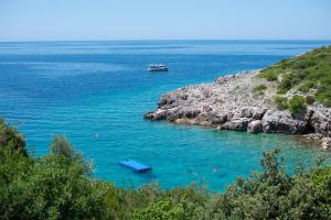 a boat in the water next to a rocky coast at Vila Veslo in Begovići