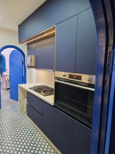 a kitchen with blue cabinets and a stove top oven at Private villa with pool in Bouznika