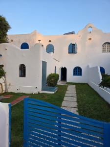 a white house with a blue fence in front of it at Private villa with pool in Bouznika