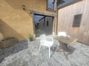a patio with a table and chairs next to a building at Maisonnette nature et sérénité in Évran