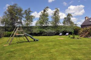 a playground with a slide and two chairs in a yard at Gite de Kergrist in Paimpol