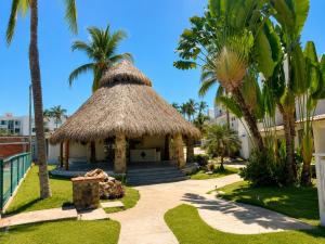 a small hut with palm trees in a resort at Hermoso apartamento en Manzanillo con alberca y cancha de tenis, Ideal para relajarse y disfrutar de una escapada tranquila en el paraíso tropical in Manzanillo
