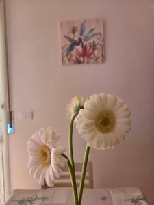 three white flowers in a vase on a table at Casa Nanà Beach in Lido Adriano
