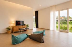 a living room with blue pillows and a television at Bali Eco Retreat in Bangli