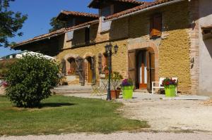 a brick house with two plants in front of it at La Ferme de Menoun in Thil