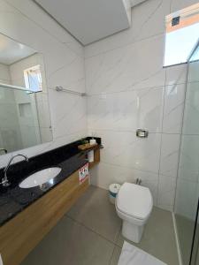 a bathroom with a white toilet and a sink at Priamo Hotel in Santo Antonio do Sudoeste +35 photos