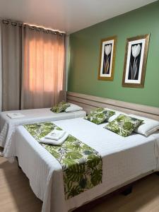two beds in a room with green walls at Priamo Hotel in Santo Antonio do Sudoeste