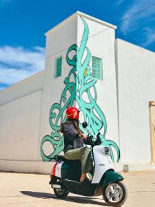 a person riding a scooter in front of a building at Wostel Djerba Downtown in Houmt Souk