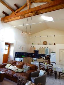 a living room with a brown couch and a kitchen at Loire Escapes - Le Grenier in Berrie