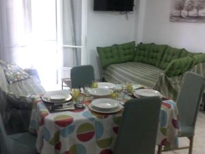 a dining room table with chairs and a green couch at ΑΚ City Apartment 1 in Ágios Rókkos