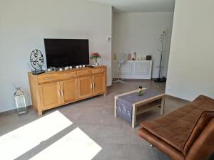 a living room with a flat screen tv on a wooden cabinet at Apartment Einliegerwohnung in Hagenthal-le-Haut