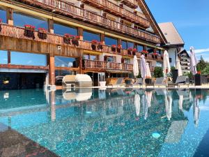 a hotel swimming pool with chairs and umbrellas at Hotel Etrier in Crans-Montana