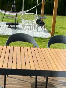 a wooden picnic table with two chairs and a swing at Domek pod Sosnową Górą in Żelazno