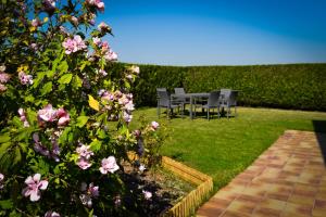 a table and chairs in a garden with pink flowers at Aan de Vleterbeke in Oostvleteren +4 photos