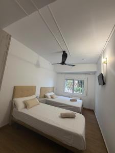 two beds in a room with white walls and a window at Miramar Viladecans in Viladecáns