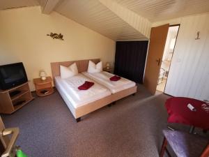 a bedroom with a white bed and a television at Holländer Mühle Rheinsberg in Rheinsberg