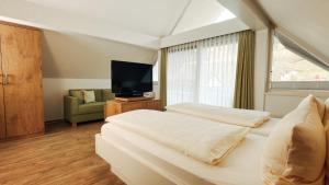 a bedroom with two beds and a tv and a couch at Hotel Garni Bergblick in Biberach bei Offenburg