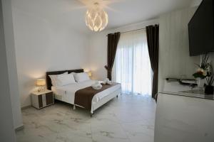 a bedroom with a large white bed and a chandelier at Villa Orkidea in Sarandë