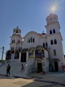 a large white building with people standing in front of it at Aleksandra Delfini Apartments in Paralia Katerinis