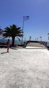 a person standing on a sidewalk near the ocean at Aleksandra Delfini Apartments in Paralia Katerinis +1 photo