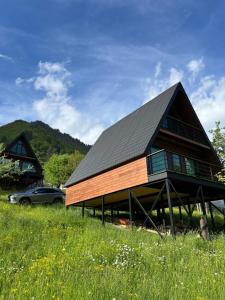 a large wooden house with a car parked in a field at Horizon Mestia - Premium Chalets With Panoramic Views in Mestia