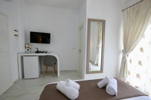 a bedroom with a bed and a desk and a mirror at Villa Orkidea in Sarandë