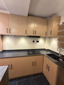 an empty kitchen with white cabinets and a sink at The Pointe Apartments in Agege