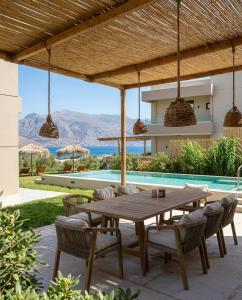 a patio with a table and chairs and a pool at Nusa Retreat - Seaview luxury residences - ideal for groups in Kissamos