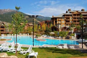 a resort with a large swimming pool with white lounge chairs at Quiet detached home steps from all the action! in Panorama