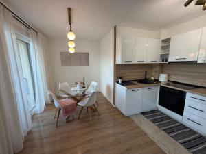 a kitchen with white cabinets and a table and chairs at Apartman I&I in Kiseljak