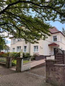 a white house with a fence in front of it at Pro Home Elia Maisonette in Bad Oeynhausen