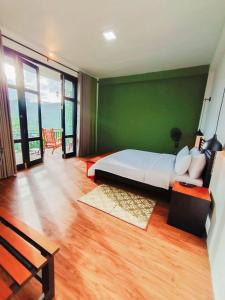 a bedroom with a large bed and a green wall at Ella Claython Hills in Ella