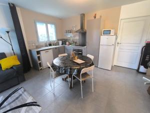 a kitchen with a table with chairs and a refrigerator at Une pause à Magny appartement de 51 m2 proche Beaune et Dijon NETFLIX gratuit in Magny-lès-Villers