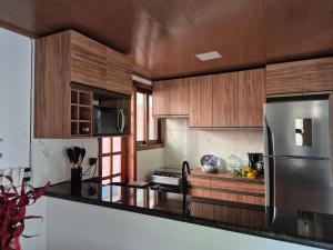 a kitchen with wooden cabinets and a stainless steel refrigerator at Privê Monte Serrat, Chalé 18 in Gravatá
