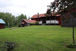 a red house with a large green yard at Bäckens Guesthouse in Älgarås