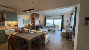 a kitchen and a living room with a table and chairs at The House On The Beach in Paleo Tsifliki