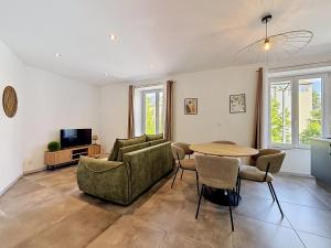 a living room with a table and chairs and a tv at L'Arrière Cour in Montbéliard