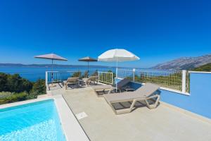a swimming pool with chairs and umbrellas on a balcony at Villa Vineyard oaza in Brela