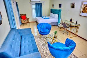 a living room with a couch and chairs and a bed at Potato Suites n Spa in Gaborone