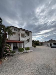 a white building with plants in a gravel driveway at More Space, More Memories -Lana Rab Apartment in Rab
